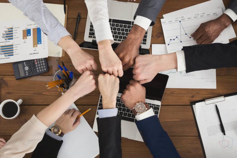 7 professionals pounding fists over work table