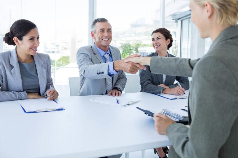 Three panel interviewers greeting job candidate