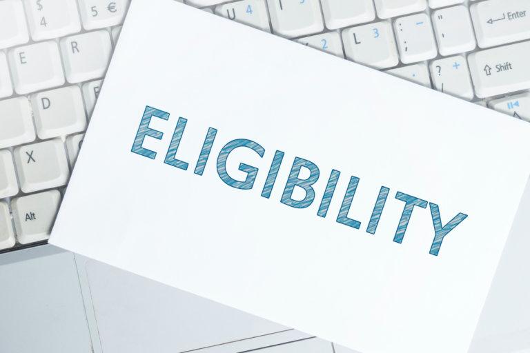 note card with eligibility written on it sitting on computer keyboard