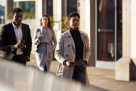 Diverse middle-class professionals walking through a city business district during their morning commute.