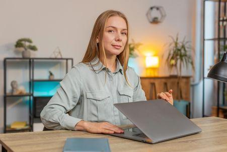 An office worker closing her laptop, representing employee workplace boundaries and effort-wage alignment.